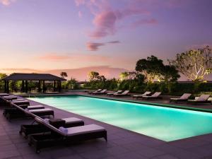 einen Pool mit Liegestühlen und einem Pavillon in der Unterkunft Fairmont Jakarta in Jakarta