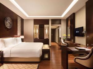 ein Hotelzimmer mit einem Bett, einem Schreibtisch und einem Schreibtisch in der Unterkunft Fairmont Jakarta in Jakarta