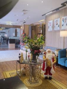 a santa claus in piedi in una stanza con un tavolo di AG Hotel a Abu Dhabi