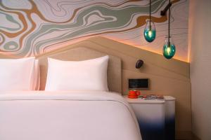 um quarto com uma cama branca e uma parede colorida em Hotel Indigo Bandung Dago Pakar by IHG em Bandung