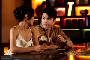 un hombre y una mujer sentados en una mesa en un bar en Wink Hotel Danang Centre - Dragon Bridge - 24hrs Stay, en Da Nang