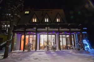 a house decorated with christmas lights in the snow at DW Janosik in Muszyna