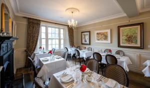 un ristorante con tavoli e sedie bianchi e un lampadario a braccio di Kells Bay House and Gardens a Kells