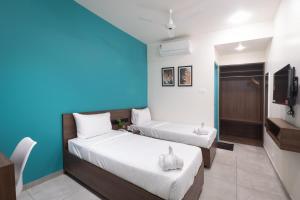 1 dormitorio con 2 camas y pared azul en The Elements Inn, en Madurai