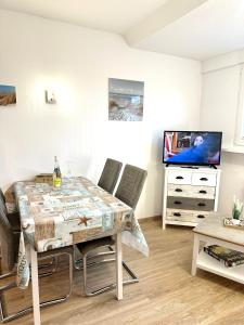 comedor con mesa y TV en Ferienwohnungen Haus Boje, en Neuharlingersiel