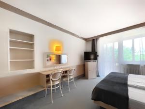 Schlafzimmer mit einem Bett, einem Schreibtisch und Stühlen in der Unterkunft WAGNERS Hotel Schönblick, C&C Hotels und Vertrieb GmbH in Fichtelberg