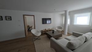 a white living room with a couch and a table at Le Belvedere By Alaïa in Crans-Montana