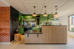 a restaurant with green walls and a counter with a table at Campanile Lille Est - Villeneuve D'ascq in Villeneuve d'Ascq