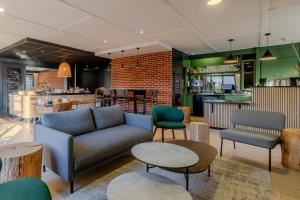 a living room with a couch and tables and a bar at Campanile Lille Est - Villeneuve D'ascq in Villeneuve d'Ascq