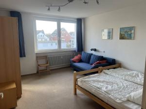 1 dormitorio con cama, sofá y ventana en Direkt am Strand in Scharbeutz, en Scharbeutz