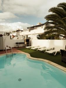 een zwembad met stoelen en een gebouw bij Surf&Sleep in Corralejo