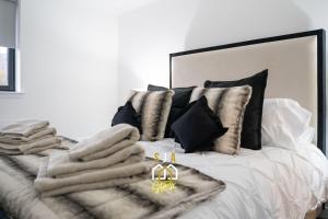 a bed with a pile of towels on it at Panacotta House - SJA Stays - Modern 1 Bed Apartment in Aberdeen