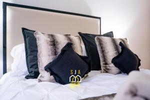 a bed with black and white pillows on it at Panacotta House - SJA Stays - Modern 1 Bed Apartment in Aberdeen