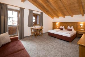 1 dormitorio con cama, mesa y sofá en Gasthaus Jakober, en Alpbach