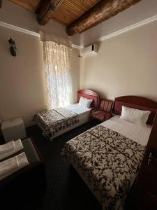 een hotelkamer met 2 bedden en een raam bij AntiqueShoxtut in Bukhara