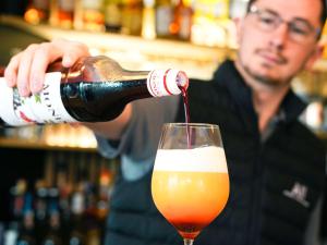 Een man die een fles bier in een glas giet. bij ibis Caen Porte d’Angleterre in Hérouville-Saint-Clair