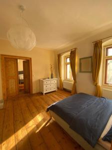 a bedroom with a bed and a dresser and windows at Apartmány v pivovaru in Kašperské Hory