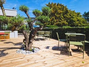 een tafel en stoelen en een boom op een patio bij ibis Caen Porte d’Angleterre in Hérouville-Saint-Clair