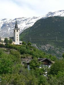 una iglesia en una colina con una montaña cubierta de nieve en La Via del Sole, en Susa