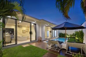 ein Haus mit Pool und Sonnenschirm in der Unterkunft The Grand Daha Luxury Villas in Seminyak