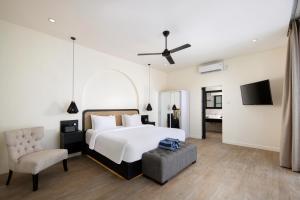 ein Schlafzimmer mit einem Bett, einem Stuhl und einem TV in der Unterkunft The Grand Daha Luxury Villas in Seminyak