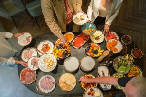 een groep mensen die rond een tafel vol eten staan bij OREA Place Seno in Praag