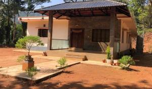 una casa pequeña con porche en un patio de tierra en Adis Home - with Beautiful Waterfalls, en Kalasa