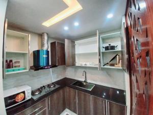 uma cozinha com armários de madeira e um lavatório em Elysium Tower Signature Serviced Apartments Islamabad em Islamabad