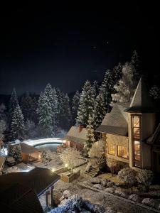 une maison avec une piscine dans la neige la nuit dans l'établissement Complex Hyzhky, à Yaremtche