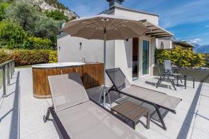 un patio con due sedie e un ombrellone di LLAC Living Nature Hotel a Limone sul Garda