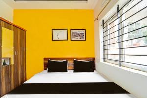 1 dormitorio con paredes amarillas y 1 cama con 2 almohadas en Super Hotel O Vijaynagar Road formerly Anmol Peace Stay, en Ooty