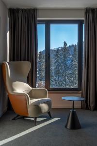 une chaise et une table dans une chambre avec fenêtre dans l'établissement Hotel Rajska dolina Jahorina, à Jahorina