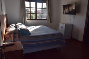 Schlafzimmer mit einem Bett mit einem Fenster und einem TV in der Unterkunft cuatro lunas hotel in Punta Del Diablo