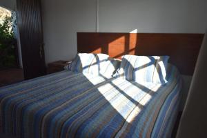 Schlafzimmer mit einem Bett mit einer blauen und weißen Bettdecke in der Unterkunft cuatro lunas hotel in Punta Del Diablo