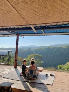 a woman and a child sitting on a wooden deck at Rinjani Houseboon in Senaru