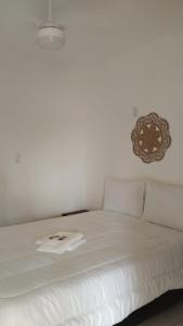 Una cama blanca con una toalla encima. en Casa Villa Real Pousada, en Cabo Frío