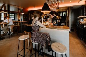 una mujer sentada en un bar con un vestido en THE HEARTS HOTEL - dein Boutique- und Event-Resort, en Braunlage