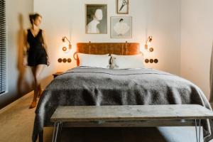 una mujer de pie junto a una cama en un dormitorio en THE HEARTS HOTEL - dein Boutique- und Event-Resort, en Braunlage