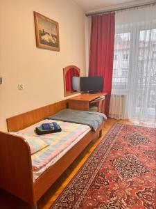 a bedroom with a bed and a desk with a television at 20 Wojskowy Szpital Uzdrowiskowo-Rehabilitacyjny w Krynicy -Zdroju in Krynica Zdrój