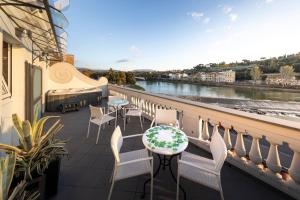 d'un balcon avec des chaises, des tables et une rivière. dans l'établissement LHP Hotel River & SPA, à Florence