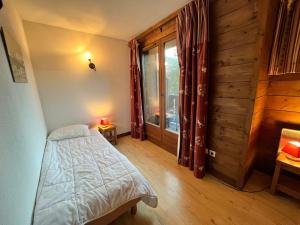 ein Schlafzimmer mit einem Bett und einem großen Fenster in der Unterkunft Appartement triplex avec piscine, parking, animaux acceptés - FR-1-624-169 in Samoëns