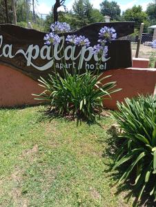 un cartel que dice "La patagonia" hotel del aeropuerto junto a las plantas en La Palapa ApartHotel, en Villa General Belgrano