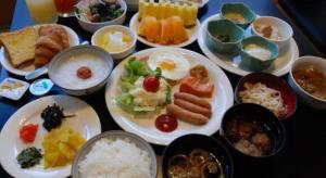 a table with plates of food and bowls of food at Albert Hotel in Akita