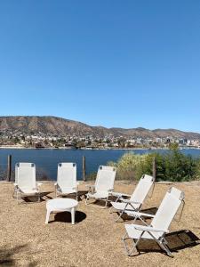 eine Gruppe weißer Stühle sowie ein Tisch und Wasser in der Unterkunft casas lake in Villa Carlos Paz