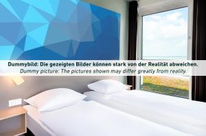 een slaapkamer met een bed en een raam bij B&B Hotel Bochum Hbf-Süd in Bochum