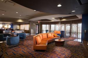 a lobby with a couch and chairs and a bar at Courtyard by Marriott Fayetteville in Fayetteville