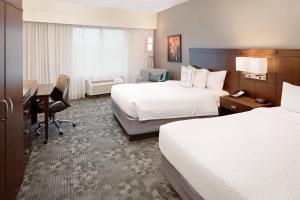 a hotel room with two beds and a desk at Courtyard by Marriott Houma in Houma