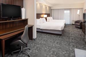 a hotel room with a bed and a desk with a television at Courtyard by Marriott Houma in Houma