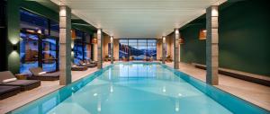 a large swimming pool in a building with chairs at Hotel Sport Klosters in Klosters