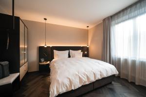 a bedroom with a large bed and a window at Schwarzer Adler - Concept Living in Vipiteno